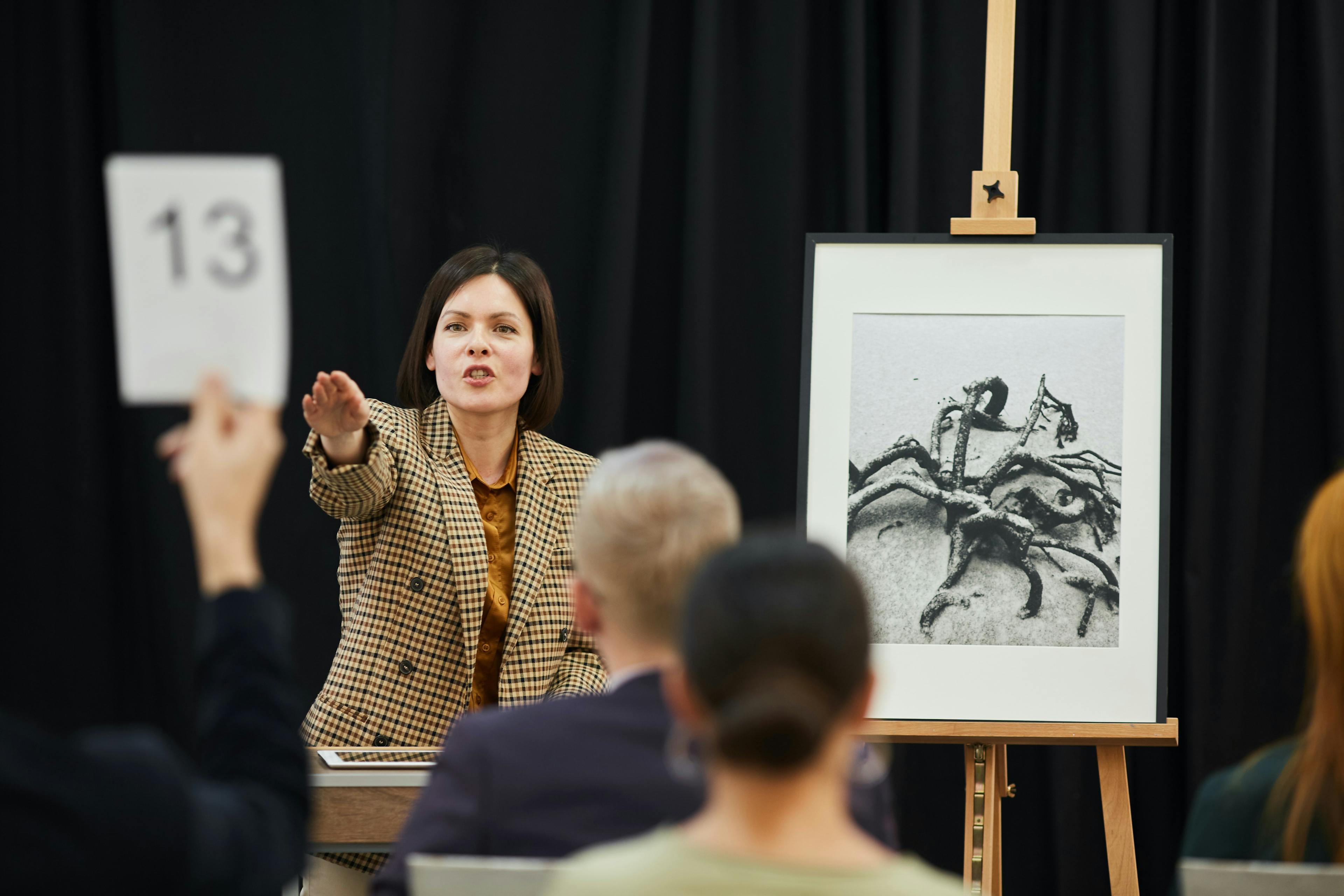 Woman auctioneer recogizing a bid from the audience
