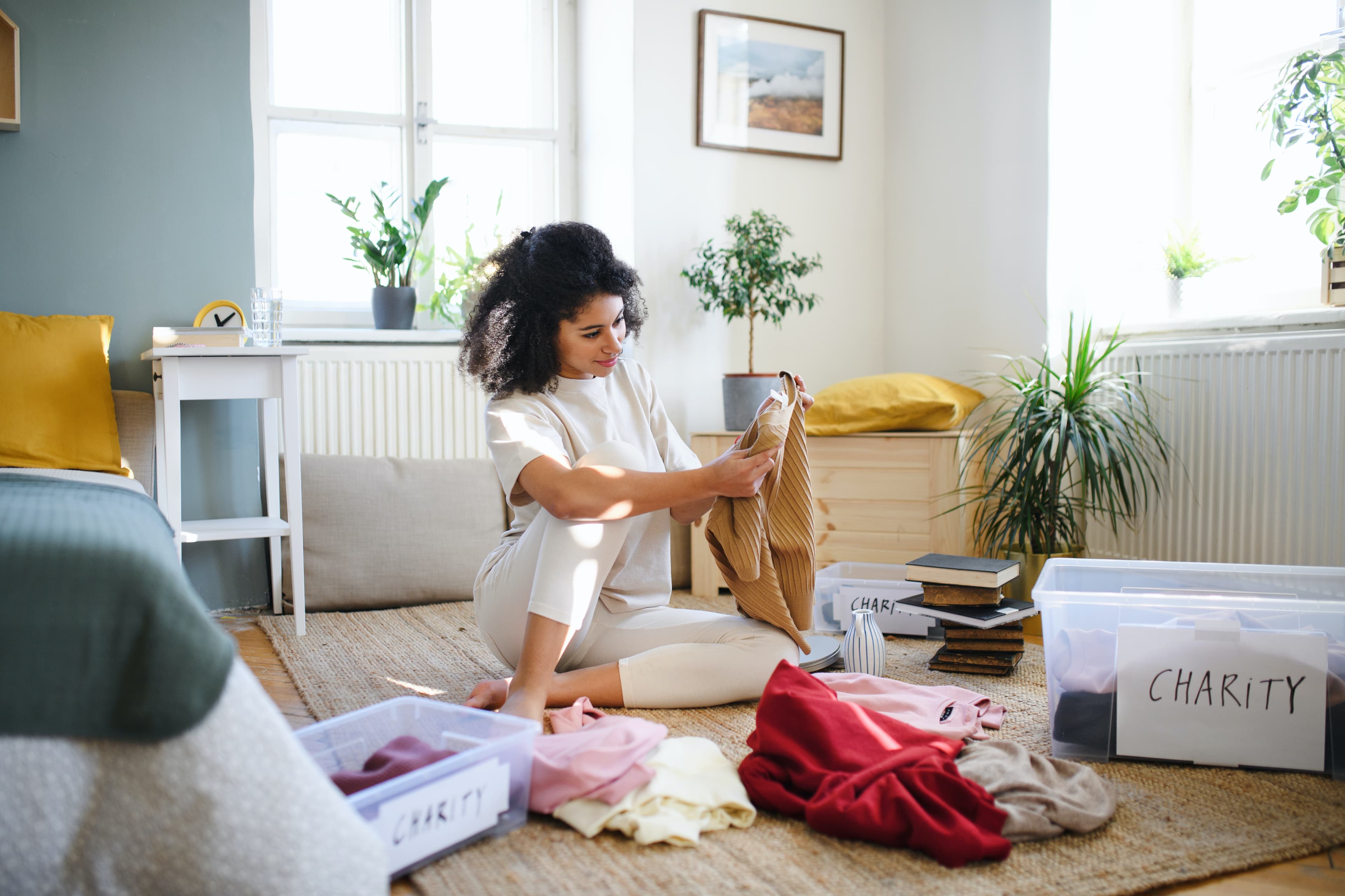 Woman sitting on the floor sorting clothing into piles